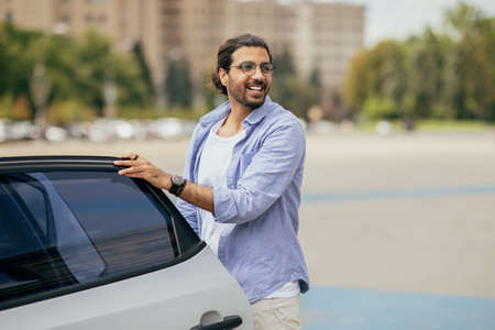 Stylish handsome middle-eastern man getting in white carの写真素材
