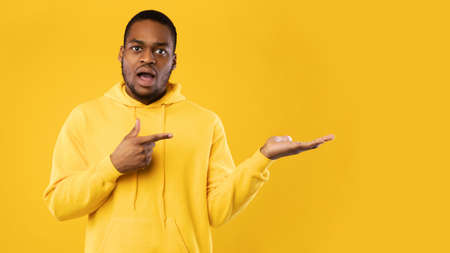 Shocked Black Man Pointing Finger Showing Copy Space, Yellow Backgroundの写真素材