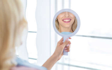 Healthy white smile in hand dental mirror reflection, closeupの写真素材
