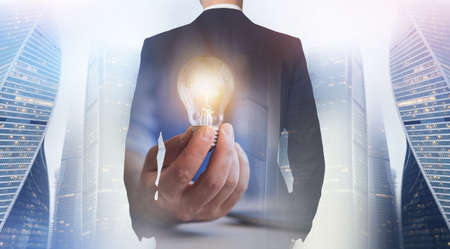 Unrecognizable confident caucasian businessman in suit in city with skyscraper and glowing light...
