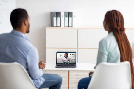 Black married couple having online session with psychologist, using laptop to communicate to marital...