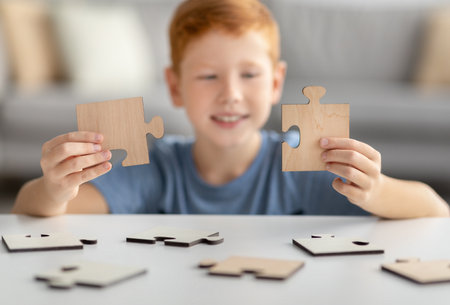 Preteen boy holding two pieces of wooden puzzlesの写真素材