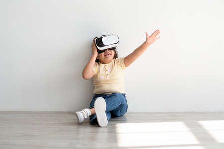 Cute Little Funny Girl Wearing VR Headset Sitting On Floor At Homeの写真素材