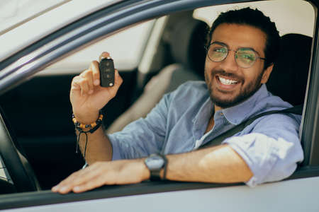 Cheerful middle-eastern long-haired guy showing car key