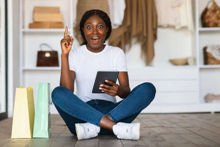African Woman Shopping Online With Tablet Pointing Finger Up Indoorの写真素材