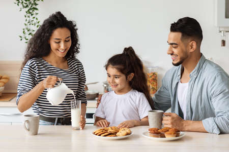 Loving mother pouring milk for her cute little daughterの写真素材