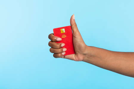 Cropped view of Afro woman holding red credit card and showing thumb up gesture on blue studio backgroundの写真素材