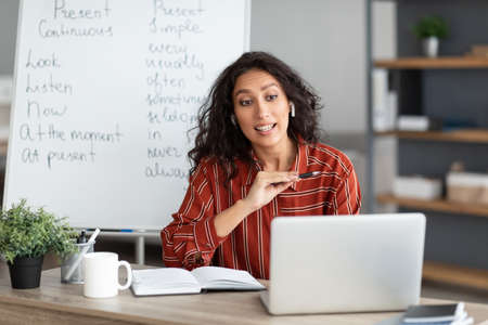 Serious English teacher having video call on laptop