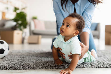 African American mom playing with her cute baby on floorの写真素材