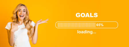 Overjoyed blonde lady pointing at GOALS loading process bar, full of hopes and expectations on...