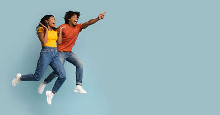 Carefree black millennial man and woman jumping in the airの写真素材