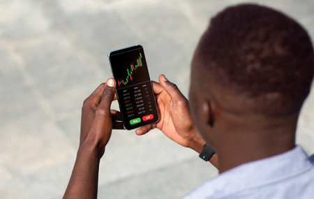 Young african american businessman checking bitcoin price on cellphoneの写真素材