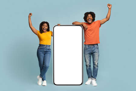 Excited african american man and woman with big mobile phoneの写真素材