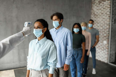 International group of people in face masks checking body temperatureの写真素材