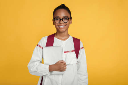 Glad smiling smart teen afro american female pupil in glasses with backpack hold tablet