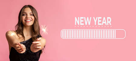 Charming young lady in dress holding sparklers, anticipating New Year party on pink background, collage with loading barの写真素材