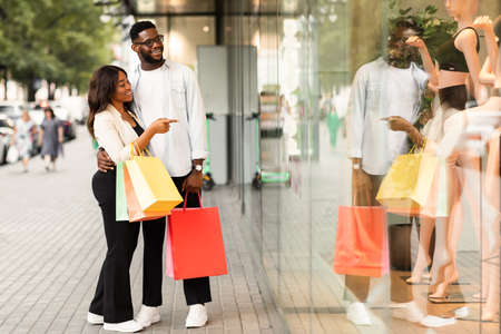 Black lady hugging man pointing at mall windowの写真素材