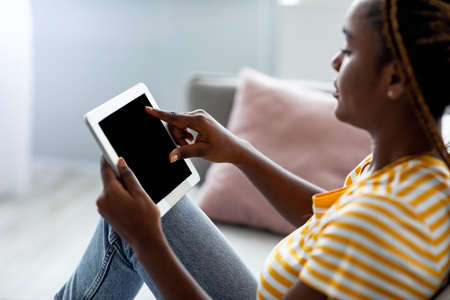 Side view of black woman using pad with empty screenの写真素材