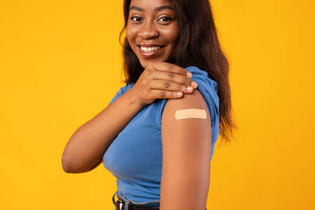 African American Lady Showing Vaccinated Arm, Yellow Studio Background, Croppedの写真素材