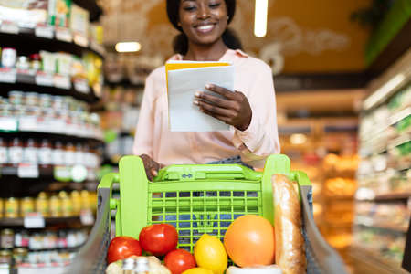 African American Lady Reading Grocery Shopping List Walking In Supermarketの写真素材