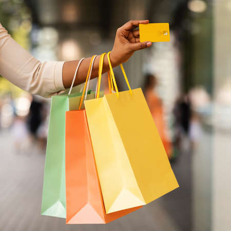 Unrecognizable black consumer holding credit card and shopping bagsの写真素材