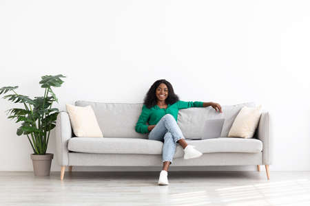 Joyful african american woman relaxing on couch at homeの写真素材