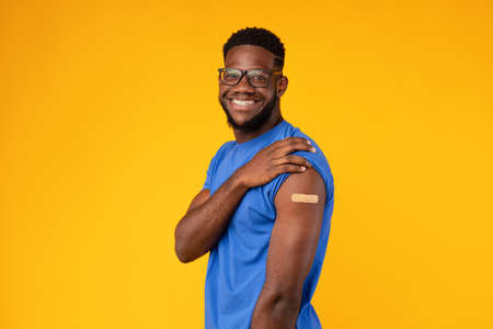Vaccinated Black Guy Showing Arm After Covid-19 Vaccination, Yellow Background