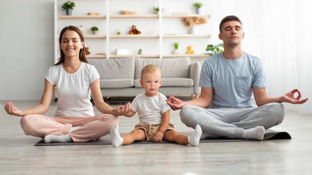 Happy Family Of Three With Little Infant Baby Meditating Together At Homeの写真素材