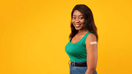 Vaccinated African American Lady Showing Arm After Vaccination, Yellow Backgroundの写真素材