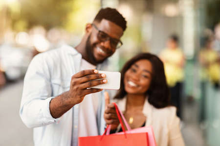 Happy black couple taking selfie after shopping at mallの写真素材