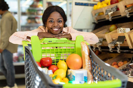 African American Woman Posing With Shop Cart In Modern Supermarketの写真素材