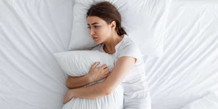 Despair unhappy young cute european woman crying, suffering from mental problems and pain in abdomenの写真素材