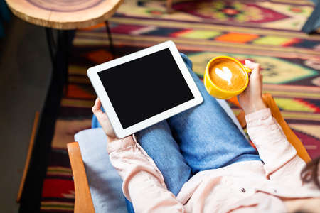 Leisure concept. Unrecognizable woman holding digital tablet with black blank screen and drinking...