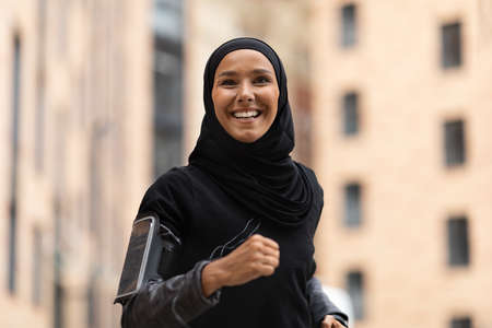 Portrait Of Happy Young Islamic Lady In Hijab Jogging Outdoors