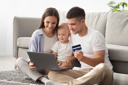 Parents And Little Baby With Laptop And Credit Card Making Online Shoppingの写真素材