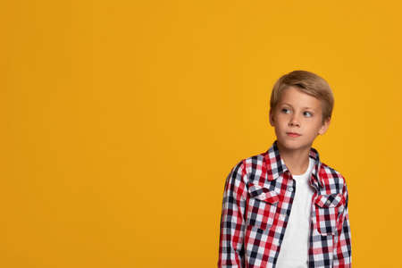 Serious calm blond teenage boy student in shirt looking at empty spaceの写真素材