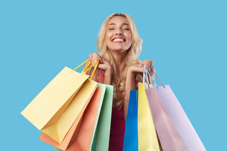 Cheerful lady holding shopping bags with new clothes