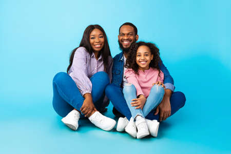African American man posing with wife and smiling daughter