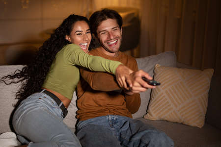Joyful Couple Watching TV Switching Channels Having Fun At Homeの写真素材