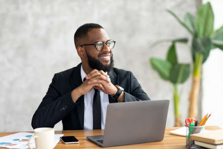 African American man using laptop thinking looking awayの写真素材