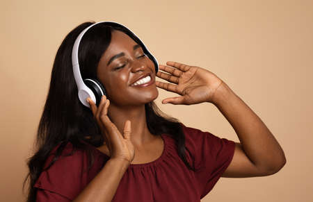 Closeup of black lady listening to music, using wireless headset