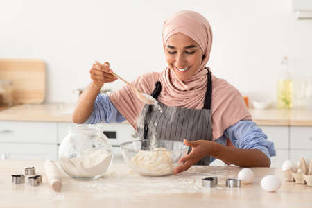 Happy Muslim Woman In Hijab Baking In Kitchen, Preparring Dough For Cookiesの写真素材
