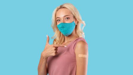 Happy Vaccinated Female In Face Mask Pointing At Arm