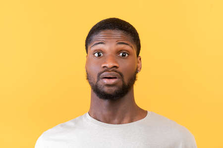 Unbelievable news. Portrait of surprised black guy opening his eyes in shock, looking at camera on...