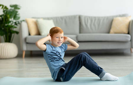 Athletic boy exercising alone at home, working on absの写真素材