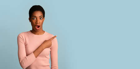 Shocking Offer. Surprised African American Female Pointing Aside With Fingerの写真素材