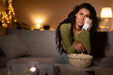 Woman Crying Watching Sad Movie Sitting On Sofa At Homeの写真素材