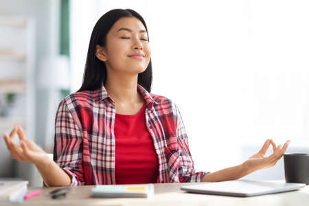 Zen. Calm Young Asian Woman Meditating At Desk In Home Officeの写真素材