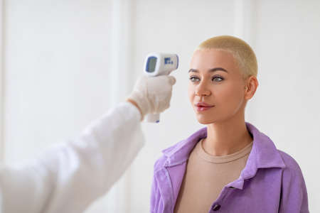 Medicine and health care concept. Doctor with contactless infrared themometer doing temperature screening for womanの写真素材