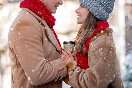 Closeup of romantic lovers drinking coffee at winter parkの写真素材
